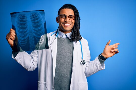 Young African American Afro Doctor Man With Dreadlocks Holding Chest Lung Xray Very Happy Pointing With Hand And Finger To The Side