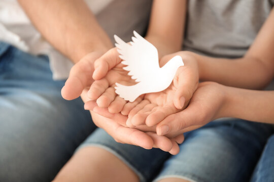 Hands of family with paper dove, closeup