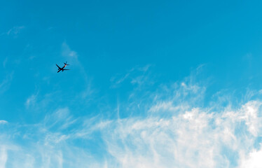 The plane is flying in the beautiful blue sky with clouds. Copy space for text