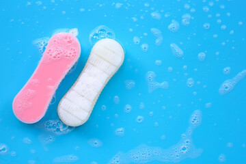 Brush for cleaning clothes with foam of powder detergent water dissolution on blue backgrond.