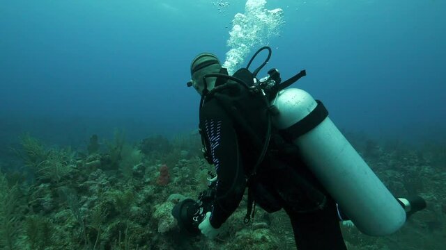 Slow motion of man photographing while exploring deep sea, scuba diver is with camera in ocean - Belize City, Belize