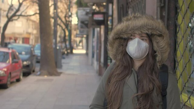 Portrait of a young student woman wearing protective mask on street. Concept of health and safety life, N1H1 coronavirus, virus protection, pandemic in china. She is affraid in a loneless street. 
