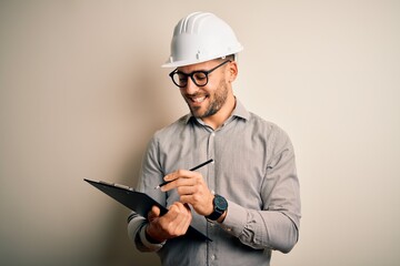 Young architect inspector man wearing builder safety helmet and using clipboard with a happy face...