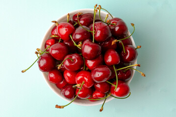Obraz na płótnie Canvas bowl full of sweet cherries on blue background close-ups