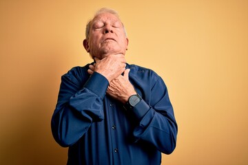 Grey haired senior man wearing casual blue shirt standing over yellow background shouting suffocate because painful strangle. Health problem. Asphyxiate and suicide concept.