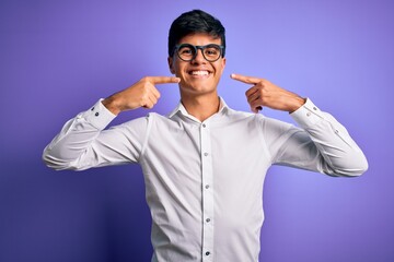 Naklejka premium Young handsome business man wearing shirt and glasses over isolated purple background smiling cheerful showing and pointing with fingers teeth and mouth. Dental health concept.