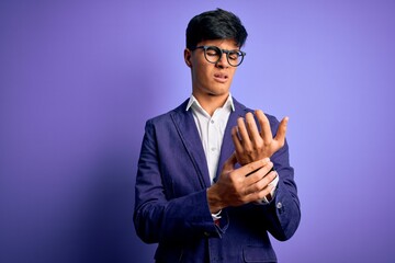 Young handsome business man wearing jacket and glasses over isolated purple background Suffering...