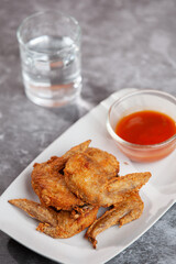 Place the fried chicken paired with chili sauce on a white plate.
