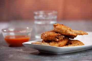 Place the fried chicken paired with chili sauce on a white plate.
