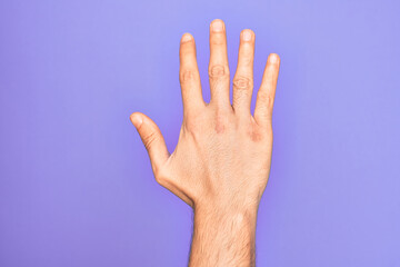 Hand of caucasian young man showing fingers over isolated purple background counting number 5 showing five fingers