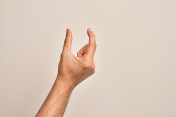 Naklejka premium Hand of caucasian young man showing fingers over isolated white background picking and taking invisible thing, holding object with fingers showing space