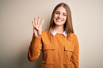 Young beautiful redhead woman wearing casual sweater over isolated white background showing and pointing up with fingers number four while smiling confident and happy.