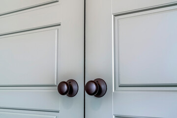 Matte black round door knobs of a double door with paneling inside a home