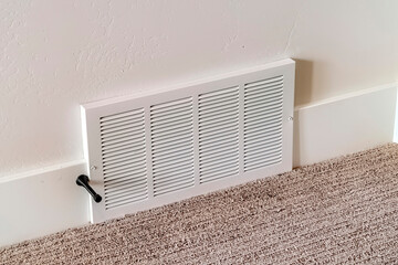 Air conditioner white plastic grille cover against wall and carpet floor - obrazy, fototapety, plakaty