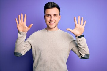 Fototapeta premium Young handsome caucasian man wearing casual sweater over purple isolated background showing and pointing up with fingers number ten while smiling confident and happy.