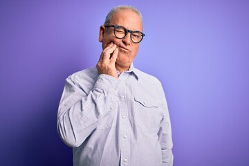 Middle age handsome hoary man wearing striped shirt and glasses over purple background touching mouth with hand with painful expression because of toothache or dental illness on teeth. Dentist