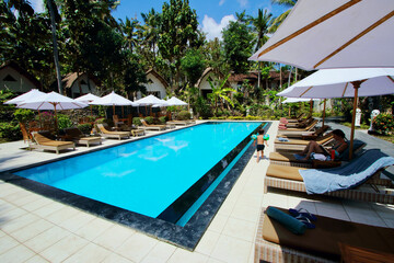 Young mum and little kid enjoying their time in a swimming pool in an amazing villa located close to Crystal Bay beach in Nusa Penida Island, Bali, Indonesia.