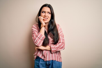 Young brunette woman wearing casual striped shirt over isolated background looking stressed and...