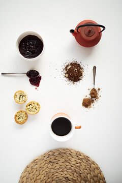 Vertical High Angle Shot Of A Small Red Teapot, Cookies, Jam, And Coffee On A White Background