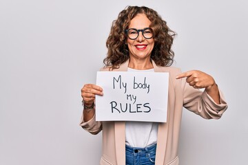 Middle age beautiful woman asking for women rights holding paper with feminist message smiling...
