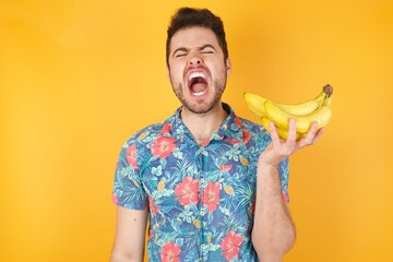 Stressful hipster man screams in panic, closes eyes in terror, keeps hands on head, finds out...