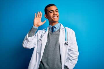 Handsome african american doctor man wearing coat and stethoscope over blue background Waiving saying hello happy and smiling, friendly welcome gesture