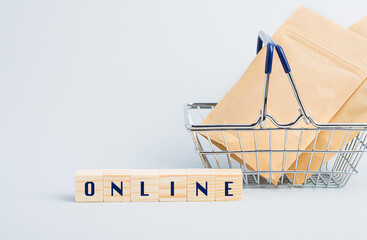 A shopping basket with paper bags and wooden blocks on a grey background.