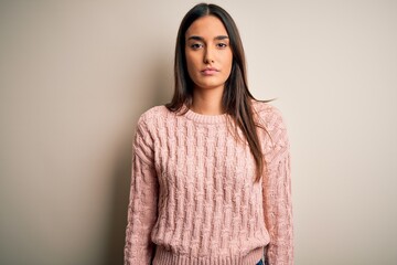 Young beautiful brunette woman wearing casual sweater over isolated white background with serious...