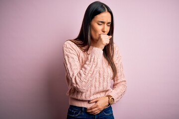 Young beautiful brunette woman wearing casual sweater over isolated pink background feeling unwell...