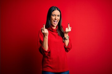 Young beautiful brunette woman wearing casual sweater over isolated red background Showing middle...