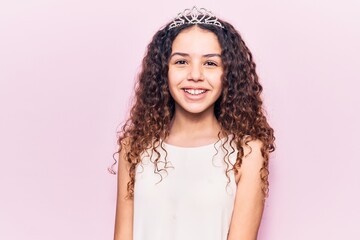 Beautiful kid girl with curly hair wearing princess tiara with a happy and cool smile on face. lucky person.
