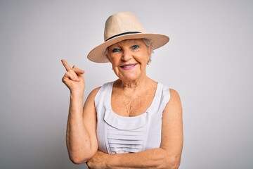 Obraz na płótnie Canvas Senior beautiful grey-haired woman on vacation wearing casual summer dress and hat with a big smile on face, pointing with hand and finger to the side looking at the camera.