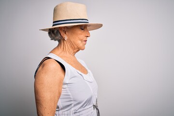 Senior beautiful grey-haired woman on vacation wearing casual summer dress and hat looking to side, relax profile pose with natural face with confident smile.