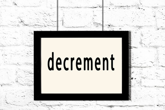 Black frame hanging on white brick wall with inscription decrement