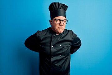 Middle age handsome grey-haired chef man wearing cooker uniform and hat Suffering of backache, touching back with hand, muscular pain