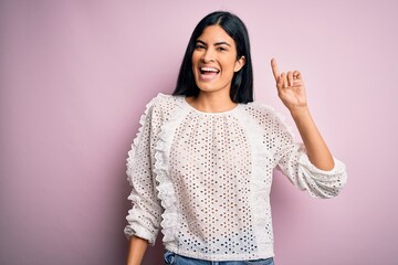 Young beautiful hispanic fashion woman wearing elegant shirt over pink background pointing finger...