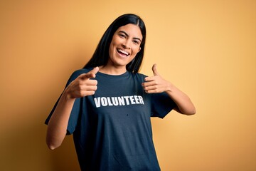 Young beautiful hispanic woman wearing volunteer t-shirt as social charity moral pointing fingers...