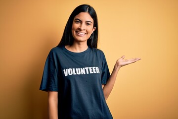 Young beautiful hispanic woman wearing volunteer t-shirt as social charity moral smiling cheerful...