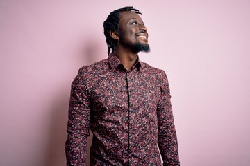 Fototapeta premium Young handsome african american man wearing casual shirt standing over pink background looking away to side with smile on face, natural expression. Laughing confident.