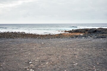 Fototapeta na wymiar Photo of black sand beach and atlantic ocean at volcanic shore. Canary islands tourism.