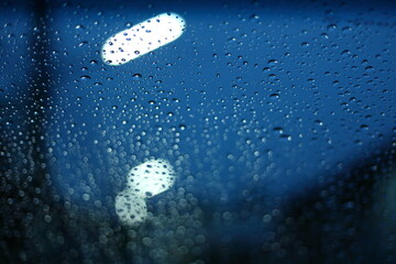 water rain drop on glass window with blur street light in night town background