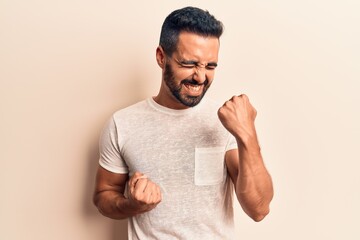 Fototapeta premium Young hispanic man wearing casual clothes celebrating surprised and amazed for success with arms raised and eyes closed
