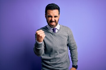 Handsome businessman with beard wearing casual tie standing over purple background angry and mad raising fist frustrated and furious while shouting with anger. Rage and aggressive concept.