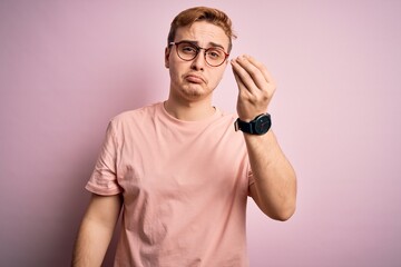 Young handsome redhead man wearing casual t-shirt standing over isolated pink background Doing Italian gesture with hand and fingers confident expression