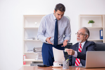 Obraz premium Stary szef i młody pracownik płci męskiej w biurze