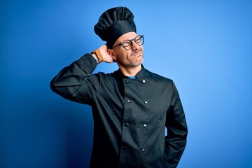 Young handsome chef man wearing cooker uniform and hat over isolated blue background Suffering of neck ache injury, touching neck with hand, muscular pain