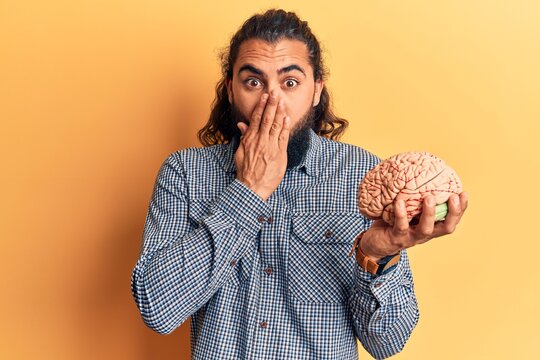 Young arab man holding brain covering mouth with hand, shocked and afraid for mistake. surprised expression