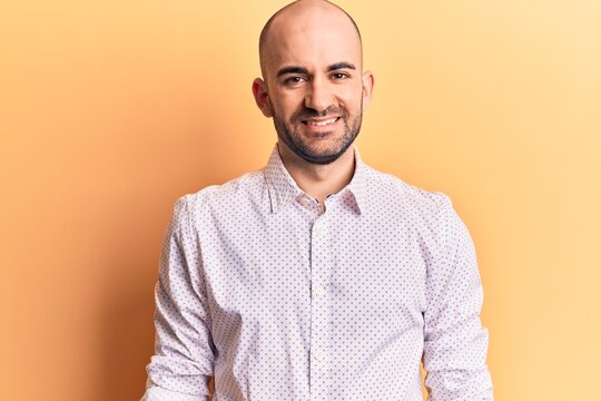Young handsome bald man wearing elegant shirt with a happy and cool smile on face. lucky person.