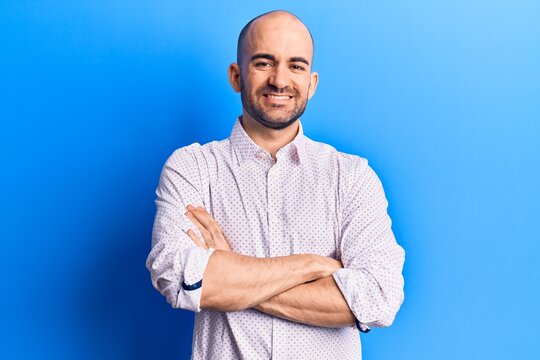 Young handsome bald man wearing elegant shirt happy face smiling with crossed arms looking at the camera. positive person.