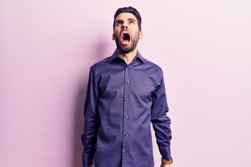 Young handsome man with beard wearing casual shirt angry and mad screaming frustrated and furious, shouting with anger. rage and aggressive concept.